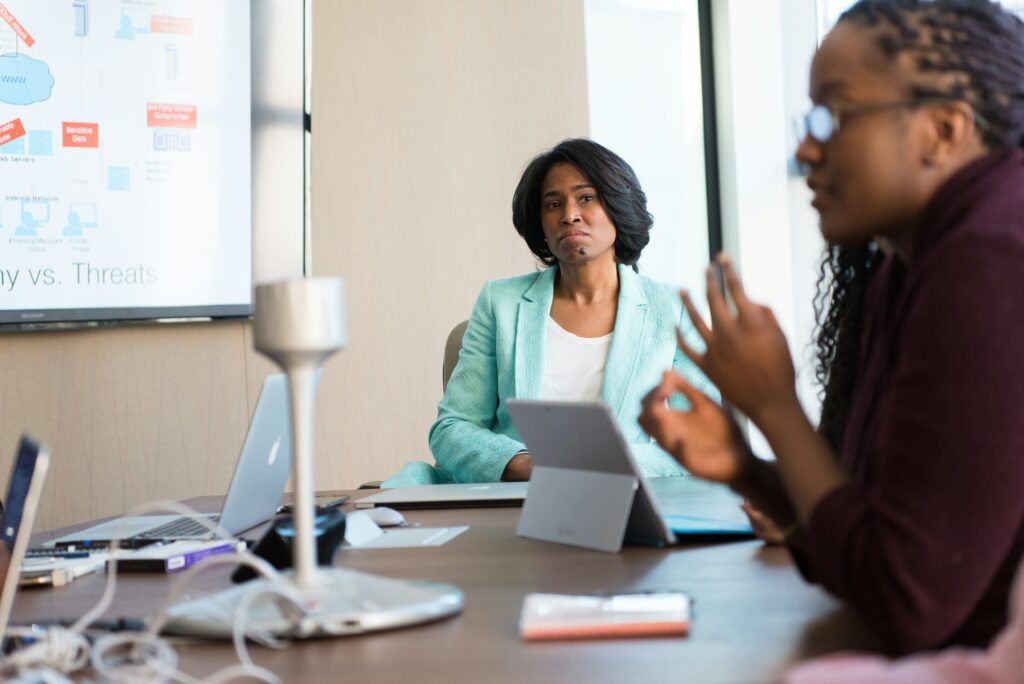 A professional team in a meeting discussing governance, risk, and compliance (GRC) in cybersecurity, with a presentation on security threats in the background.